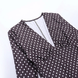 Detail view of the V-neckline and white polka dot pattern on a dark brown dress