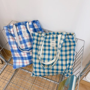 Close-up of cotton tote bags with blue checkered and floral patterns in a metal basket