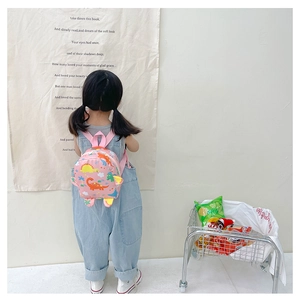 Toddler girl wearing pink cartoon dinosaur backpack with waterproof fabric in a studio
