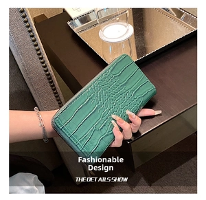 Detail of green crocodile embossed long wallet with silver chain strap and zipper