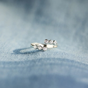 Macro shot of silver ring with six sparkling round zircons on blue denim background