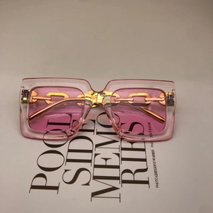 Detail of pink transparent square sunglasses with golden metal chain on temple arm