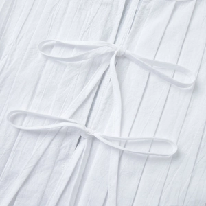 Gros plan détaillé du tissu plissé blanc en coton avec de délicats nœuds à nouer