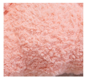 Close-up of soft pink plush fabric texture on a croissant pillow showing fluffy fibers
