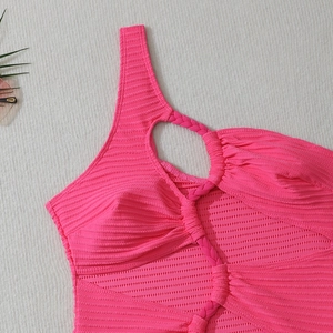 Détail d'un maillot de bain rose néon côtelé avec bretelle tressée et découpe latérale