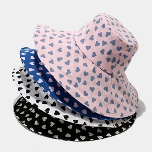 Stack of four colorful heart print bucket hats in pink, blue, white and black colors