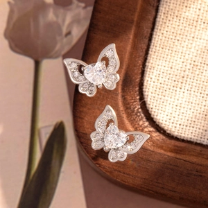 Elegant butterfly titanium steel earrings with heart zircon on a wooden tray