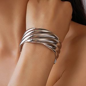 Detail of silver wavy textured wide cuff bracelet showing layered metallic folds on wrist