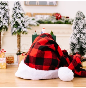 Macro detail of red and black plaid Christmas hat with white plush trim on wooden surface