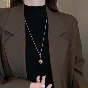 Detail shot of a minimalist gold ball pendant necklace on a refined metal chain