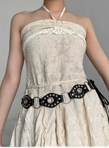Detail of cream halter lace dress with ruffles and black punk studded eyelet belt