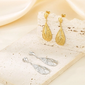 Detailed view of teardrop hollow earrings with inlaid stones on travertine stones