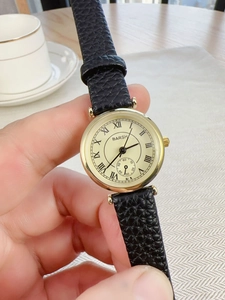 Close-up of classic Roman numeral dial and gold-tone case on black leather strap watch
