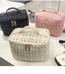 Three elegant tweed toiletry bags in black, pink, and white on a marble vanity top