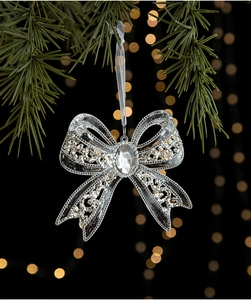 Silver glitter bow ornament with faux crystal gem on green pine tree branch