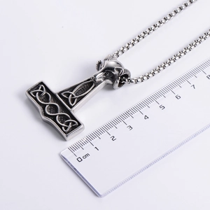 Vintage silver Thor's Hammer pendant with ram head and Celtic knot on white background