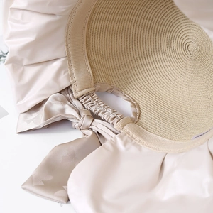 Women's foldable straw sun hat with large champagne satin bow and elastic band detail