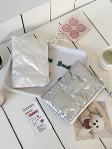 Detail of bow-embossed storage pouches with pearl zipper pulls in white and silver