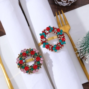 Detail of gold Christmas wreath napkin rings with red and green crystals on a festive table