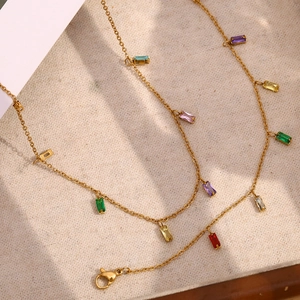 Détail d'un collier doré avec pierres précieuses rectangulaires colorées et fermoir mousqueton
