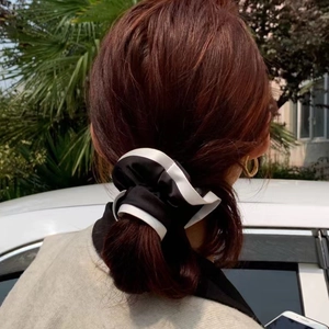 French style black and white satin scrunchie shown on a ponytail in an outdoor setting