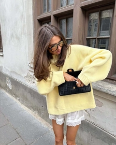 Street style shot of a yellow oversized knit sweater paired with a black quilted chain bag
