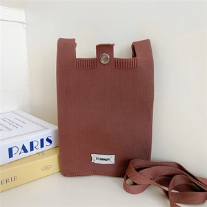 Close-up of brown knit phone bag showing metal clasp and brand fabric label detail