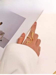 Close-up of gold-plated snake ring with scale texture worn by a model in a luxury setting