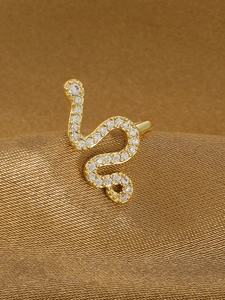 Dettaglio macro di un orecchino a serpente dorato con pavé di zirconi bianchi brillanti