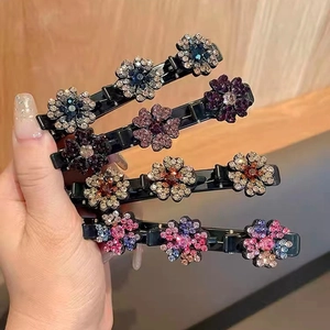 Dettaglio di quattro mollette per capelli a fiore con strass tenute in mano per l'acconciatura