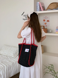Polka dot canvas tote bag with red trim and FUTURE patch shown on shoulder in bedroom