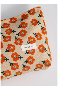 Close-up of floral corduroy makeup bag showing detailed orange flower print and texture
