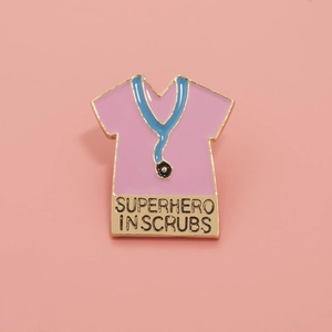Detailed macro view of pink enamel superhero nurse brooch with gold trim and blue stethoscope