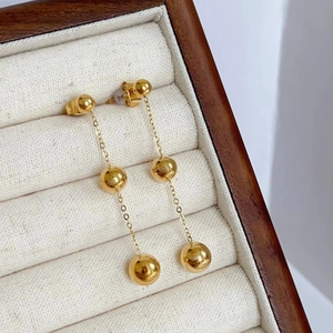 Detailed shot of 18K gold plated triple ball drop earrings in a luxury jewelry box