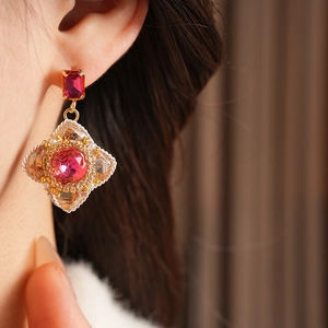 Close-up of vintage palace-style earrings with red gemstones and pearl accents