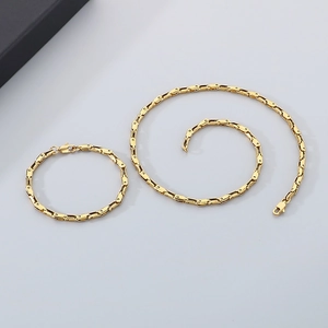 Flat lay of gold plated stainless steel chain necklace and bracelet jewelry set