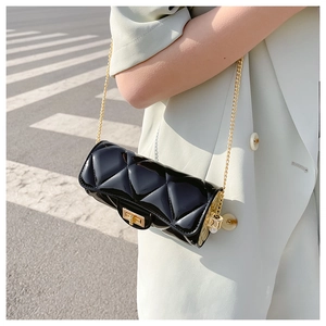 Detail shot of a black quilted cylindrical bag with golden chain and square buckle