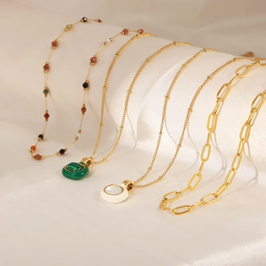 Gold plated necklaces set with green malachite and white shell pendants on white silk