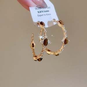Macro shot of 925 silver hoop earrings with tiger eye stones and sparkling crystals