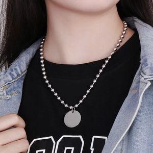 Gros plan d'un collier à billes argenté avec un pendentif rond vierge sur un mannequin