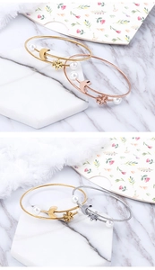 Detailed close-up of gold bracelets with moon charms and pearls on marble background