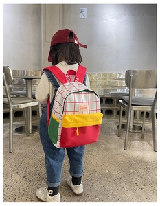 Rear view of a child wearing a colorful canvas backpack with red and white checkered pattern