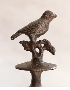 Detailed view of a vintage cast iron bird ornament with rustic bronze texture and finish