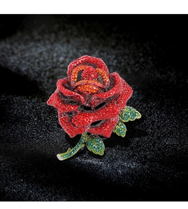 Detailed close-up of rose brooch with red petals and green leaves on black background