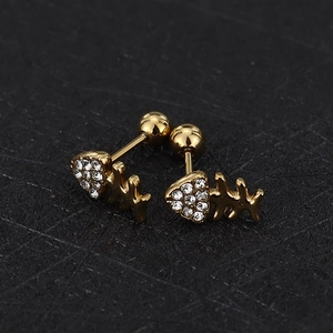 Macro shot of gold fishbone cartilage stud earrings with white zircon stones and screw balls