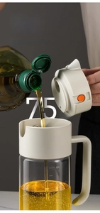 Detail of 75mm wide mouth glass oil bottle showing capacity scales and pouring action