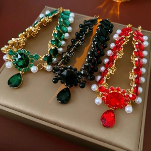 Close-up of vintage gold necklaces with emerald, ruby, and onyx pendants and pearls