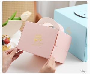 Detailed view of pink and blue cake boxes with gold foil embossing and handle