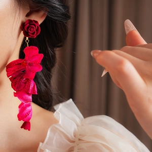 Gros plan d'un mannequin portant des boucles d'oreilles fleurs rouges artistiques