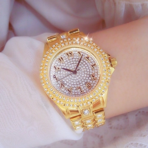 Montre de luxe dorée pour femme avec cristaux et cadran à chiffres arabes au poignet